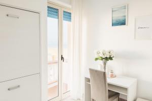a white dining room with a table and a vase of flowers at Aria di sale B&B in Marina di Strongoli +39 photos