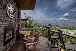 a balcony with chairs and a fireplace with a view at "Land of the Free, Home of the Brave" Double Luxury Treehouse for 12 Near Dollywood & Pigeon Forge in Catlettsburg