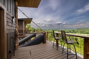a balcony with two chairs and a view of the forest at "Land of the Free, Home of the Brave" Double Luxury Treehouse for 12 Near Dollywood & Pigeon Forge in Catlettsburg