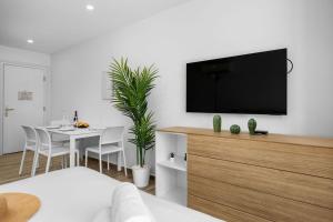 a living room with a tv and a table with chairs at Modern Studio w/ Pool, Gym & Rooftop Palm Beach in Palm-Eagle Beach