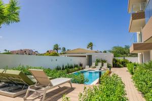 a backyard with a swimming pool and chairs and a house at BRAND NEW Studio w/Pool, GYM, Rooftop @ Palm Beach in Palm-Eagle Beach