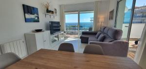 ein Wohnzimmer mit Tisch und Stühlen und einem Fernseher in der Unterkunft Ático con gran terraza, vistas y plaza de parking in Blanes