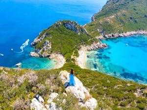 a person sitting on a rock overlooking a beach at Villa Anafoufou Afionas with private heatable pool in Afionas