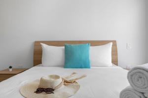 a bed with a straw hat and towels on it at NEW Modern Studio w/ Pool & Gym I Walk 2 PalmBeach in Palm-Eagle Beach +19 photos