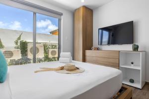 a bedroom with a white bed and a television at NEW Modern Studio w/ Pool & Gym I Walk 2 PalmBeach in Palm-Eagle Beach