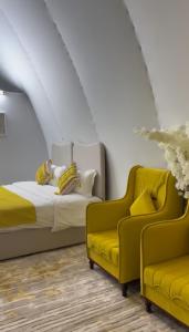 2 sillas amarillas y 1 cama en una habitación en Amara Camp, en Al Raka