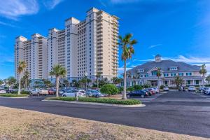 un grand immeuble d'appartements avec des voitures garées dans un parking dans l'établissement The Beach Club 1001C, à Gulf Highlands