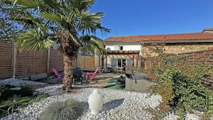 une cour arrière avec un palmier et une maison dans l'établissement Le clos du bon temps, à Sainte-Marie-de-Vaux