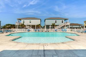 a swimming pool with chairs and a house in the background at Gulf Breeze in Rockport