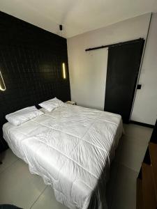 a bedroom with a white bed with a black wall at Modern Apartment in São Caetano do Sul in São Caetano do Sul