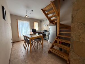 eine Küche mit einem Tisch und eine Treppe in einem Zimmer in der Unterkunft Paimun 2 - Andarlibre in San Martín de los Andes