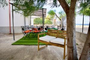 a wooden bench sitting next to a tree next to a table at Aria di sale B&B in Marina di Strongoli