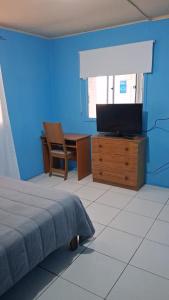 a bedroom with a bed and a desk with a television at Hostal Nancy in Mejillones