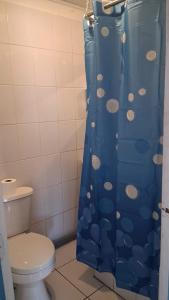 a bathroom with a blue shower curtain with a toilet at Hostal Nancy in Mejillones +21 photos