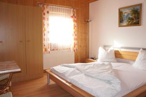 a bedroom with a white bed and a window at Ferienhaus Riegler in Sankt Georgen bei Neumarkt
