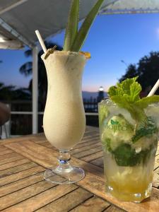 a cocktail and a drink on a wooden table at Réveil face à la mer - Plage à 2 min - Résidence calme in Gourbeyre