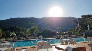 vistas a una piscina con mesas y sillas en Cavalinho Branco 305 suíte com varanda, en Águas de Lindóia