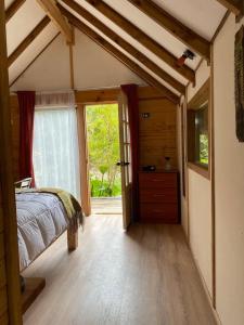 a bedroom with a bed and a large window at Posada de Expediciones Kahuel in Chaitén