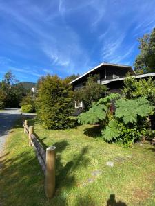 a house with a fence in front of a yard at Posada de Expediciones Kahuel in Chaitén
