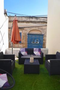 een patio met een bank, een parasol en gras bij San Nikola Getaway in Sliema