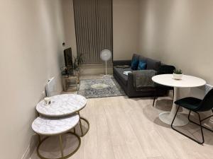 ein Wohnzimmer mit einer Couch und zwei Tischen in der Unterkunft Centenary Netho - Leeds City Centre in Central Station