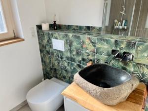 a bathroom with a black sink and a toilet at okoTime - Studio mit Dachterrasse in Birkenwerder +15 photos