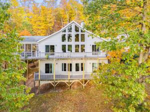 a white house on a hill with trees at Mountain retreat w deck, game room & dog-friendly in Hedgesville