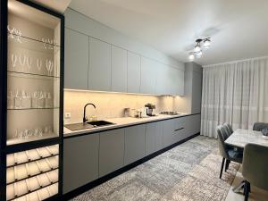a kitchen with white cabinets and a dining table at CityView Apartment in Chişinău