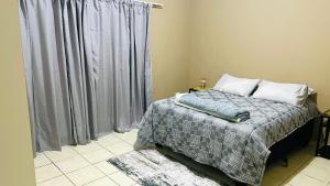 Un dormitorio con una cama y una ventana con cortinas. en Serene guesthouse, en Manzini