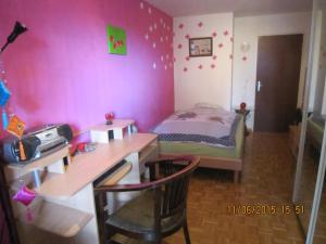Schlafzimmer mit einem Schreibtisch und einem Bett mit rosa Wänden in der Unterkunft Schönes Zimmer in der City Basel in Basel