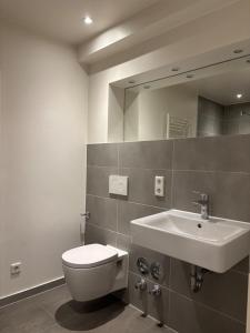 a bathroom with a sink and a toilet and a mirror at Loftbude in Hürth
