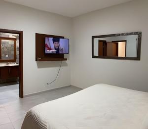 a bedroom with a bed and a tv on a wall at Casa El Dorado - a 2 minutos de la Playa Miramar in Colonia Miramar