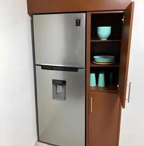 a refrigerator in a kitchen next to a shelf at Casa El Dorado - a 2 minutos de la Playa Miramar in Colonia Miramar