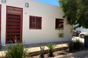 a white building with red shutters on the side of it at Casa El Dorado - a 2 minutos de la Playa Miramar in Colonia Miramar