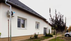 una casa blanca con un coche aparcado al lado en Éva Pihenőház Tiszaföldvár, en Tiszaföldvár