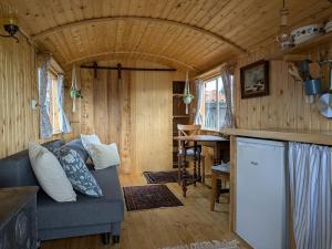 a living room with a couch and a table at Herdershut 'Het Schoehuis', vlakbij zee in Sint Maartensbrug