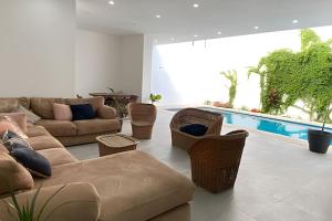 a living room with a couch and chairs and a pool at Casa El Tular - Alberca priv / a 5 min de la playa in Colonia Miramar