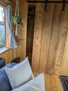 a bedroom with wooden walls and a bed with a pillow at Shepherd's hut Het Schoehuijs in Sint Maartensbrug +14 photos