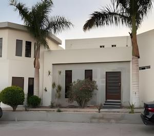 a white house with palm trees in front of it at Casa El Tular - Alberca priv / a 5 min de la playa in Colonia Miramar