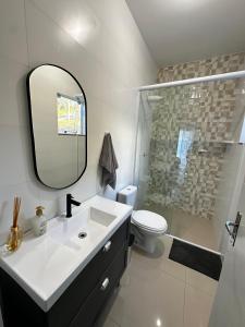 a bathroom with a sink and a toilet and a mirror at Casa moderna em Videira in Videira