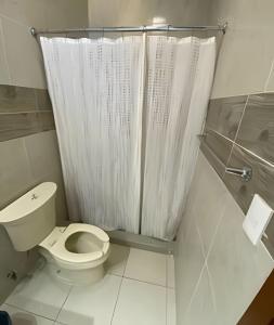 a bathroom with a toilet with a shower curtain at Casa Madre Perla - a 2 min de la Playa Miramar in Colonia Miramar
