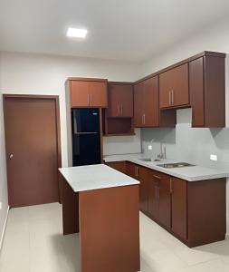 a kitchen with brown cabinets and a black refrigerator at Casa Madre Perla - a 2 min de la Playa Miramar in Colonia Miramar