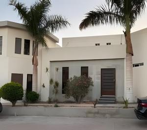 a house with palm trees in front of it at Loft El Tular - a 5 minutos de la Playa in Colonia Miramar