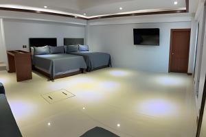 a bedroom with two beds and a television in it at Loft El Tular - a 5 minutos de la Playa in Colonia Miramar