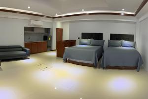 a bedroom with two beds and a couch and a kitchen at Loft El Tular - a 5 minutos de la Playa in Colonia Miramar