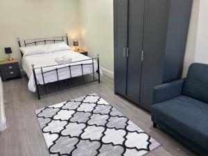 a bedroom with a bed and a couch and a chair at Tooting Stays in London