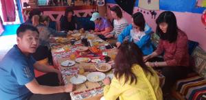 eine Gruppe von Menschen sitzt um einen Tisch herum und isst in der Unterkunft Home khamlia in Merzouga + 6 Fotos