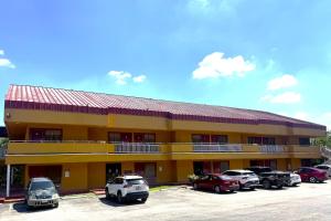 ein gelbes Gebäude mit auf einem Parkplatz geparkten Autos in der Unterkunft Homegate Studios & Suites San Antonio Medical Center in San Antonio