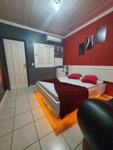 a bedroom with a bed with red walls at Motel A 2 in Criciúma