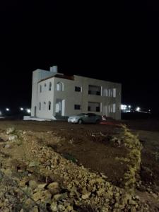 um edifício com um carro estacionado em frente dele à noite em The Fog mountain em Kerak